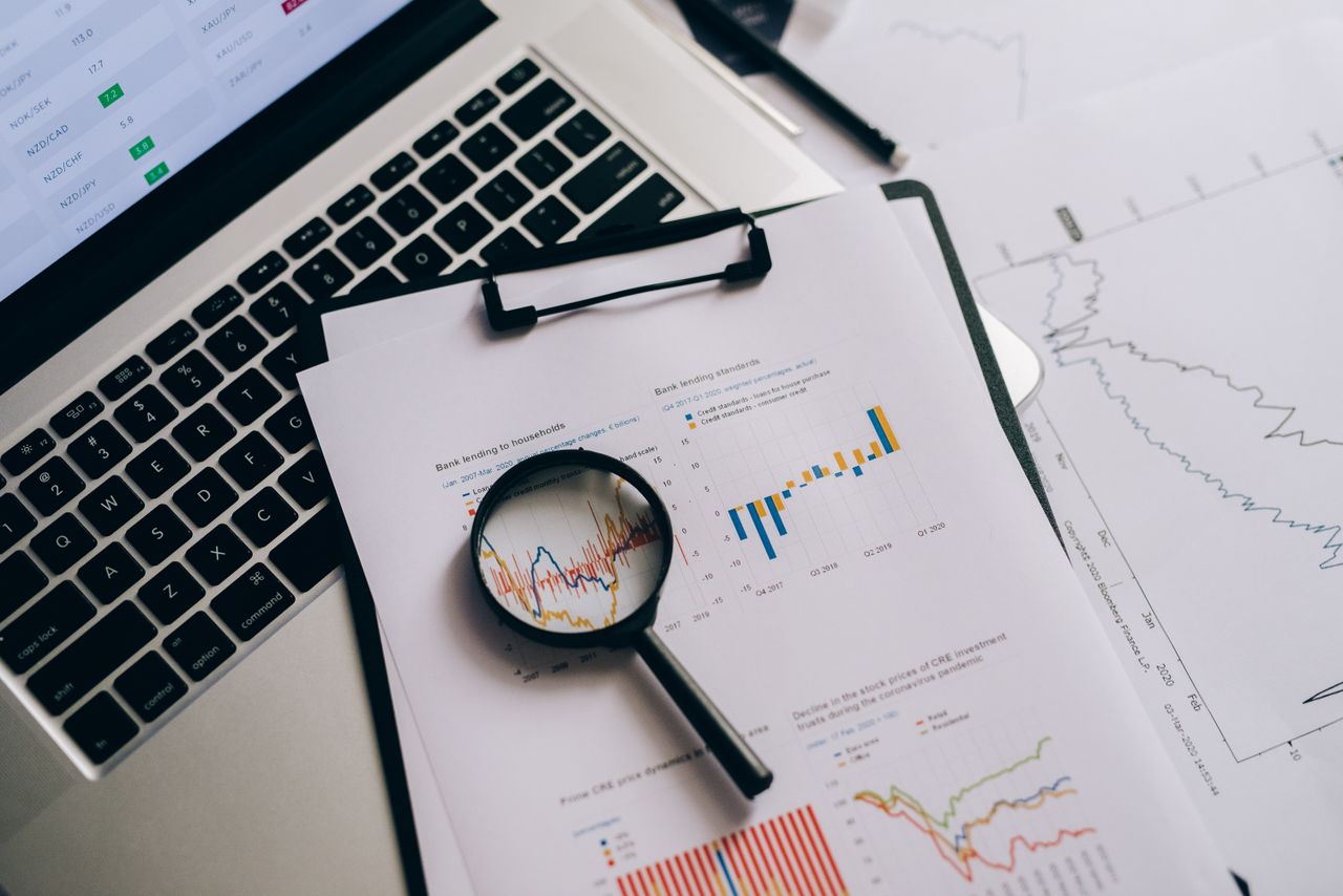 creative Overhead view of financial charts, laptop, and magnifying glass, ideal for business analysis themes.